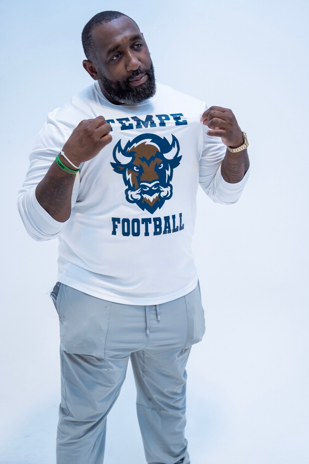 Portrait of Coach Sean Freeman holding out his white Tempe Football shirt with the buffalo logo